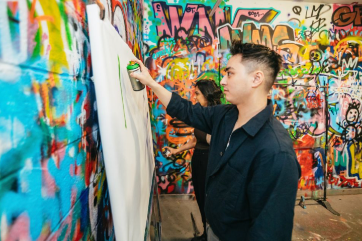 a young boy standing in front of a graffiti covered wall