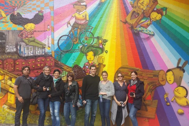 group posing in front of graffiti piece on wall