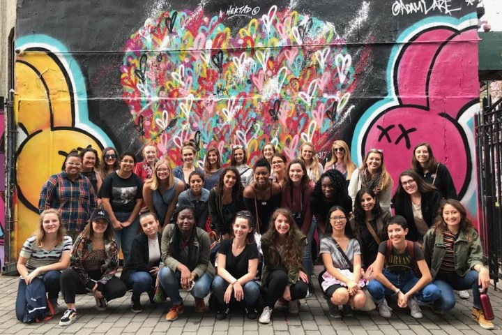 a group of people standing in front of a graffiti covered wall