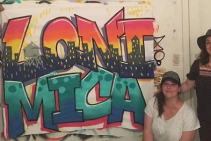 girls standing in front of graffiti piece