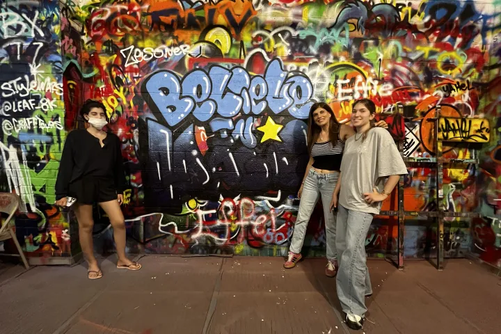 a group of people standing next to a graffiti covered wall