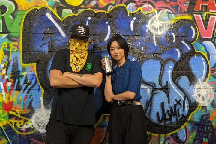 a person standing in front of a graffiti covered wall