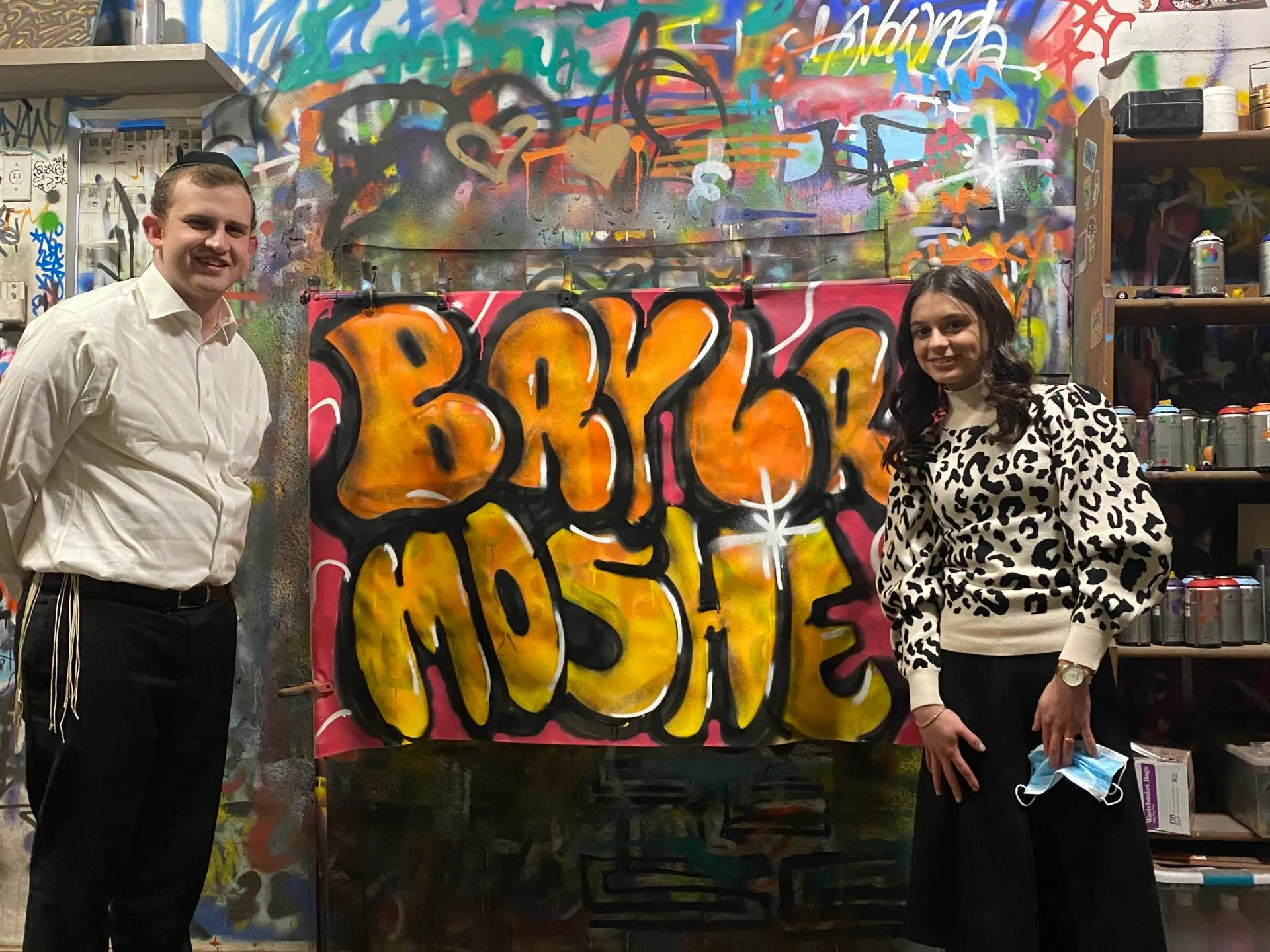 a man standing in front of a store filled with lots of graffiti