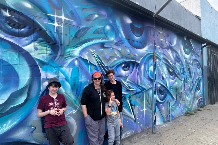 a person standing next to a graffiti covered wall