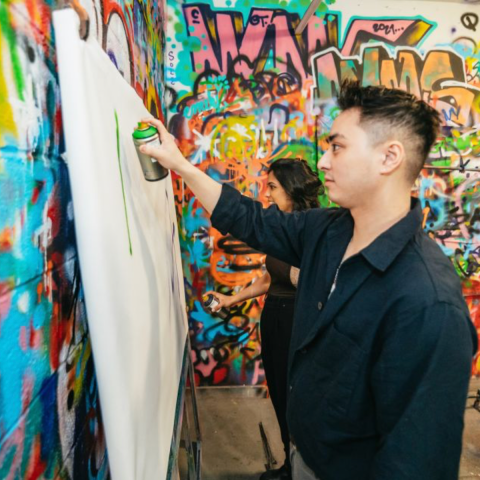 a young boy standing in front of a graffiti covered wall