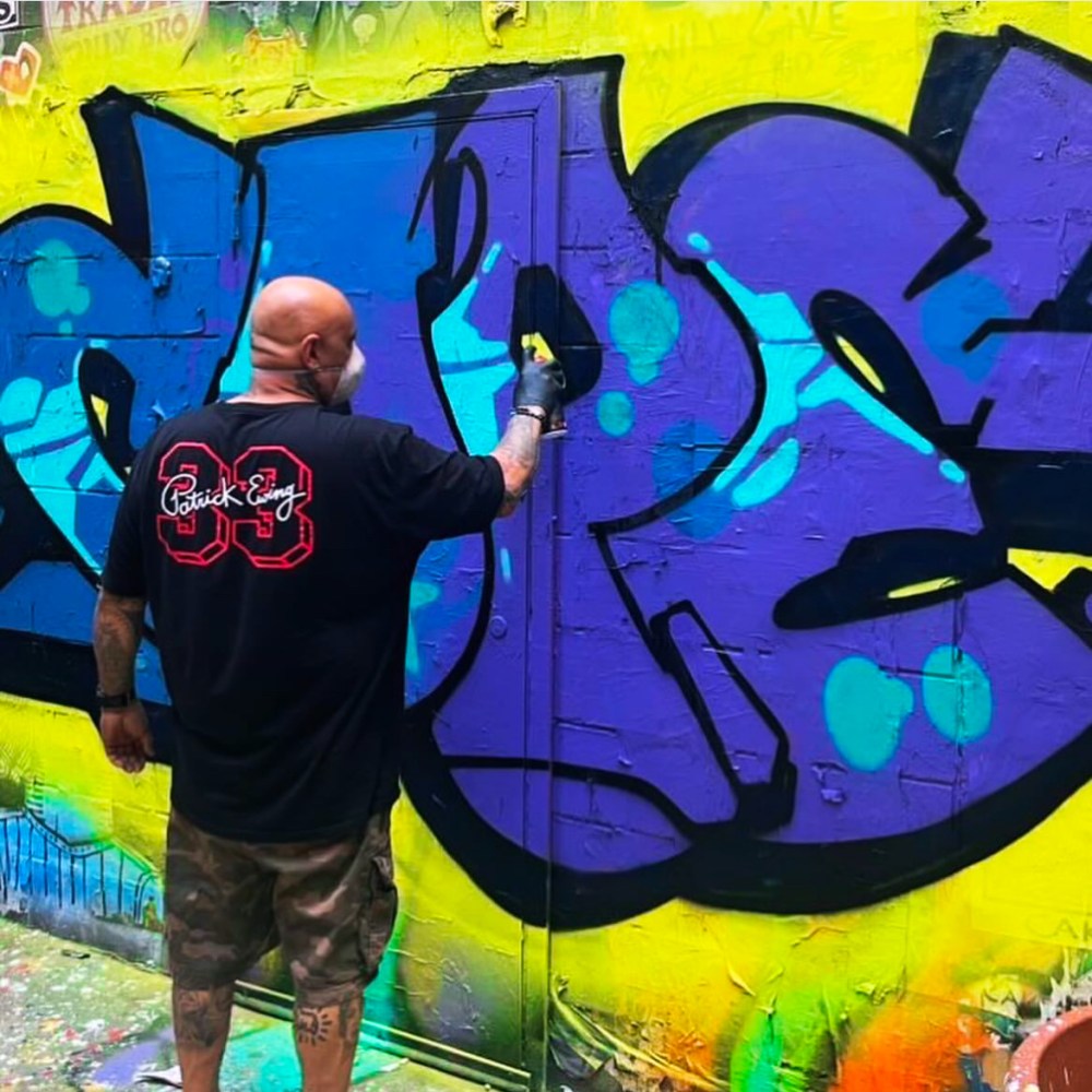 a man standing in front of a graffiti covered wall