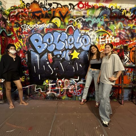 a group of people standing next to a graffiti covered wall